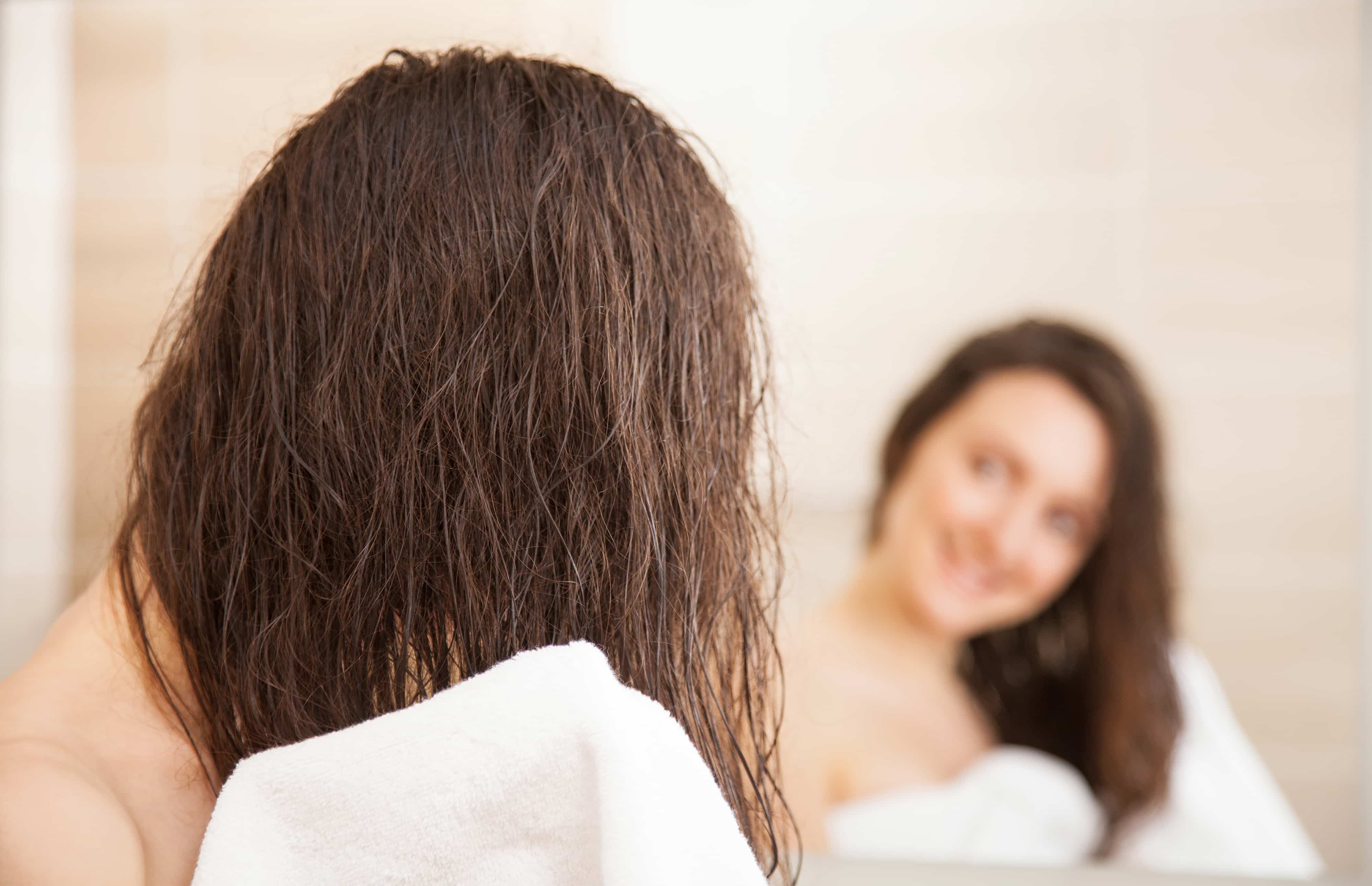 鏡に映る髪をタオルドライする女性後姿