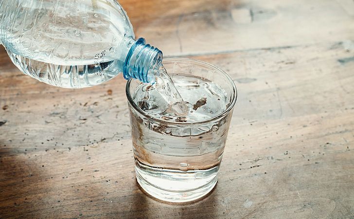 グラスにペットボトルの水を注いでる