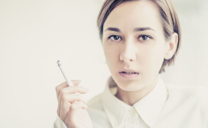 女性が火のついたタバコを右手で持っている姿